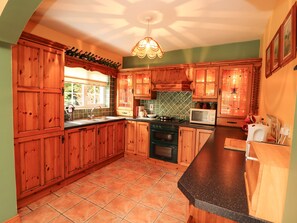 A kitchen with wooden cabinets, a black countertop, a stove, and a microwave. - The Lodge (Beaufort)