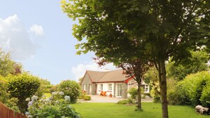 A house with a stone facade, a red roof, and a well-maintained lawn. - The Lodge (Beaufort)