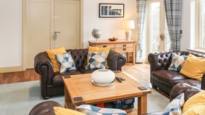 Een woonkamer met leren banken, een houten salontafel en een wereldbol op een bijzettafeltje.