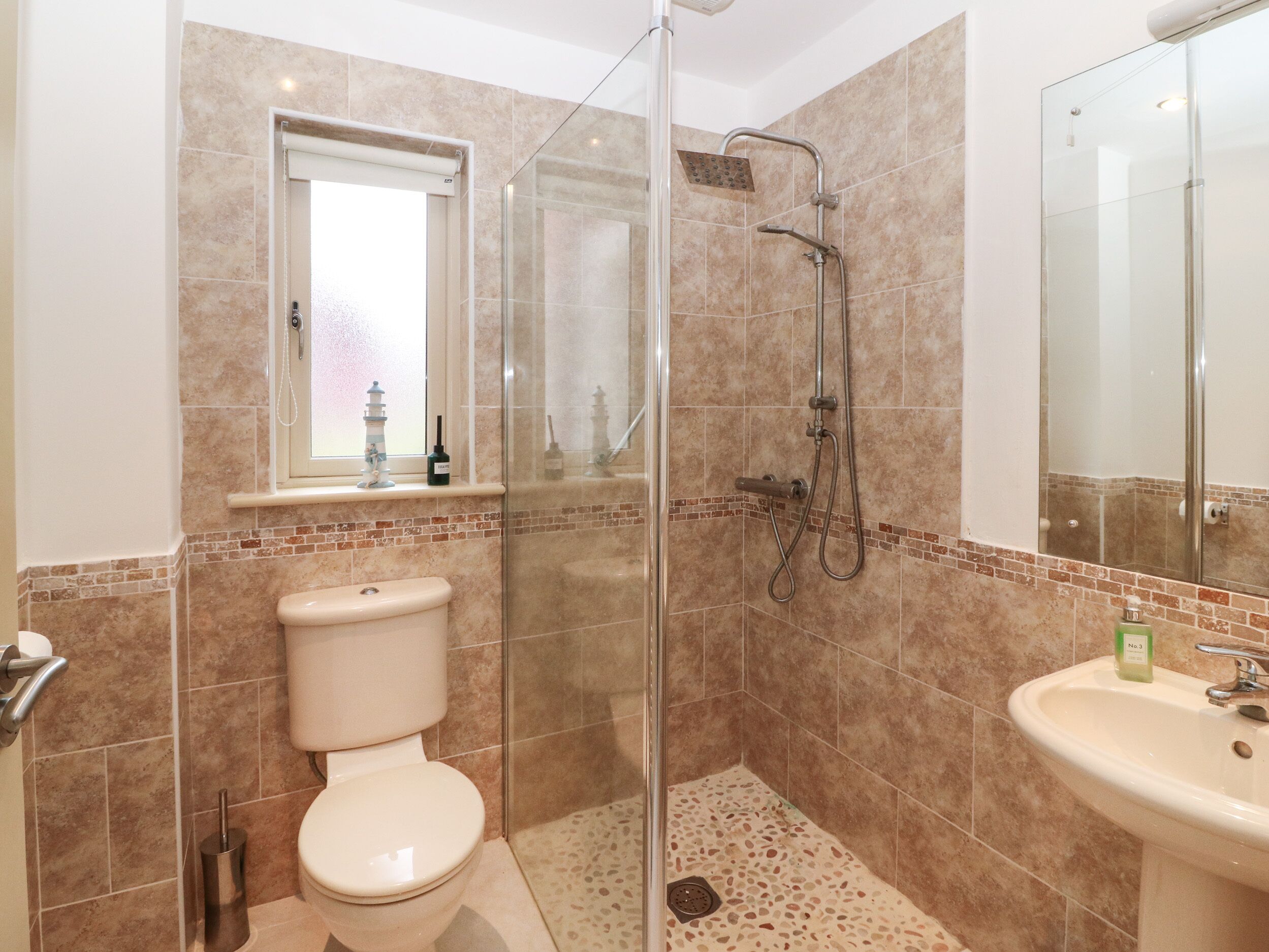 A bathroom with a glass-enclosed shower, a toilet, and a sink.