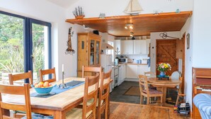 Una cocina acogedora con armarios de madera, una mesa de comedor con sillas y vistas al exterior.