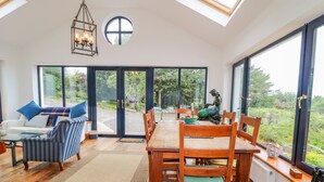 Una habitación amplia con comedor, un conjunto de sofás y grandes ventanales con vistas al exterior.
