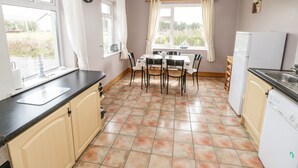 A kitchen with a dining table, chairs, a refrigerator, and a washing machine.
