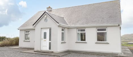 A single-story house with a gabled roof, a front door, and two windows on the side.