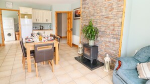 A compact living space with a dining area, kitchenette, and a seating area with a sofa and a fireplace. - Artigallivan (Killarney)