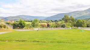 A rural landscape with a grassy field, a road, and distant hills. - Artigallivan (Killarney)
