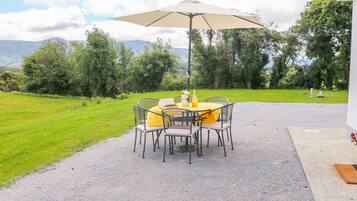 Relax in a serene outdoor setting with a round table and comfortable seating under a spacious umbrella.