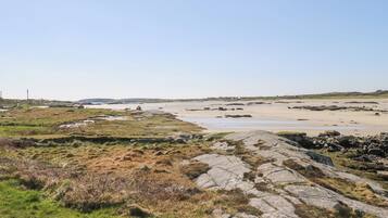 Eine Küstenlandschaft mit felsigem Gelände und einem Sandstrand.
