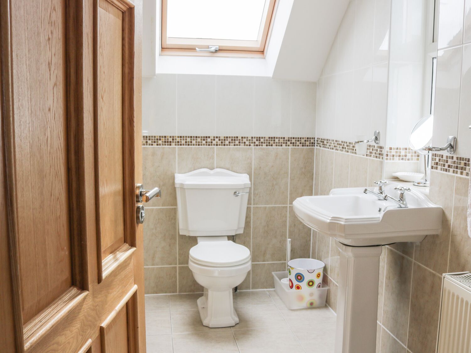 Un bany amb vàter, un lavabo i un finestral a la part superior del vàter.
