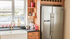 A kitchen with a stainless steel refrigerator, a sink with a faucet, and wooden cabinets.