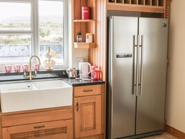 Una cocina con refrigerador de acero inoxidable, un lavamanos con grifo y armarios de madera.