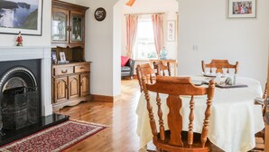 A dining area with a round table, wooden chairs, and a fireplace.
