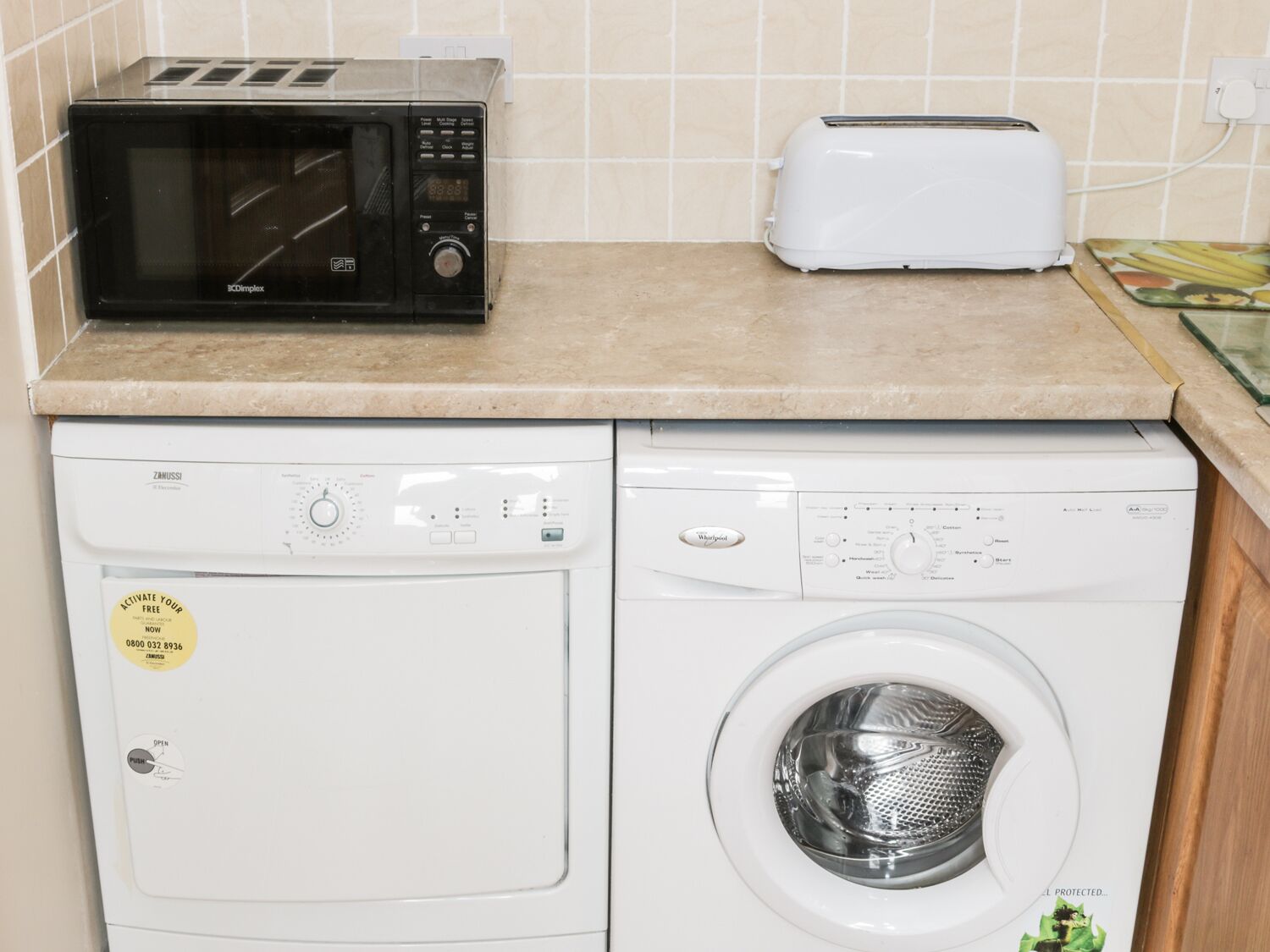 Une cuisine équipée d’un four à micro-ondes, d’un grille-pain et d’un lave-linge.
