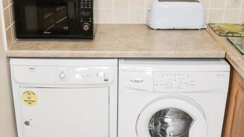 Une cuisine équipée d’un four à micro-ondes, d’un grille-pain et d’un lave-linge.