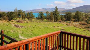 Une terrasse en bois offrant une vue sur un lac et des montagnes.