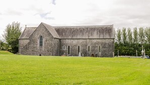 A stone church with a large lawn in front. - Cherry Tree Cottage (Ballintober)