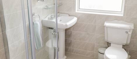 A bathroom with a glass shower enclosure, a pedestal sink, and a toilet.
