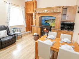 Una sala de estar acogedora con chimenea, armarios de madera, una mesa de comedor preparada para cuatro personas y un sofá de cuero cómodo.