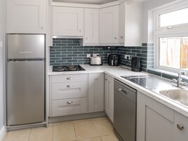 Una cocina moderna con armarios blancos, un refrigerador de acero inoxidable, un lavavajillas y un ventanal que proporciona luz natural.