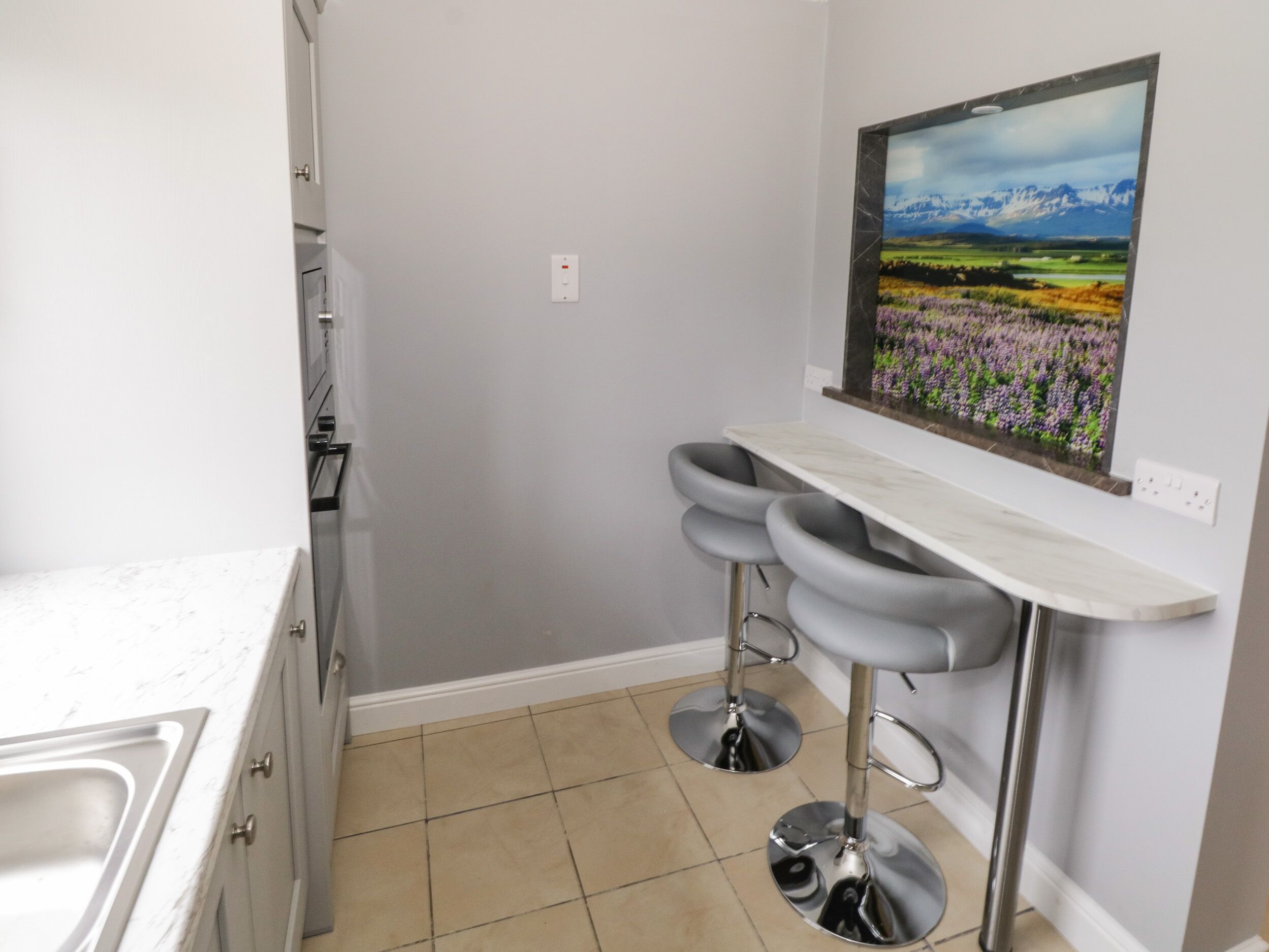 A kitchen with a white countertop, a sink, and a window with a landscape view.