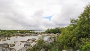 Un paysage naturel caractérisé par un lit de rivière rocheux et une végétation luxuriante.