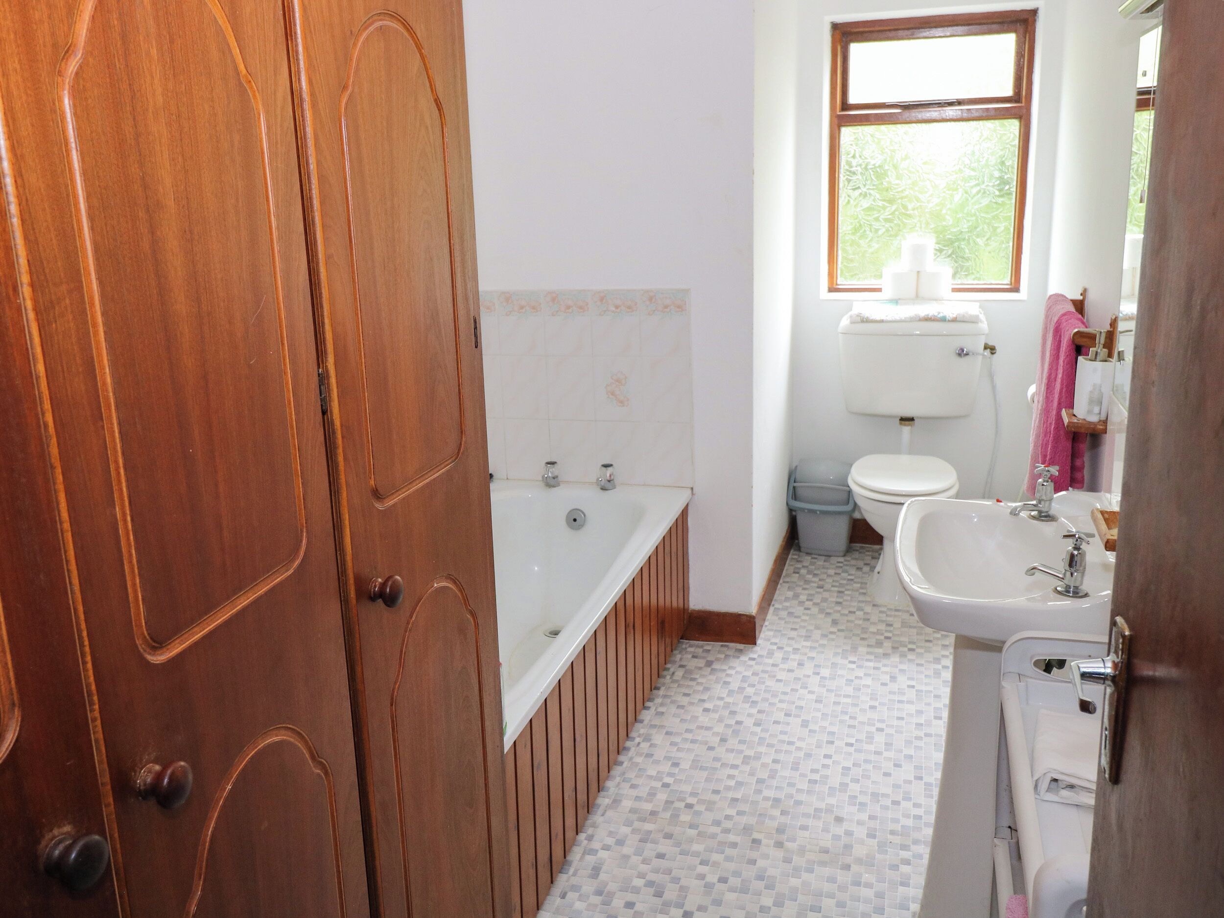 A bathroom with a wooden door, a bathtub, a toilet, and a sink.