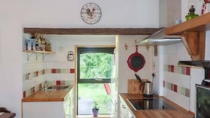Een keuken met houten aanrecht, een fornuis en een raam met uitzicht op groen.