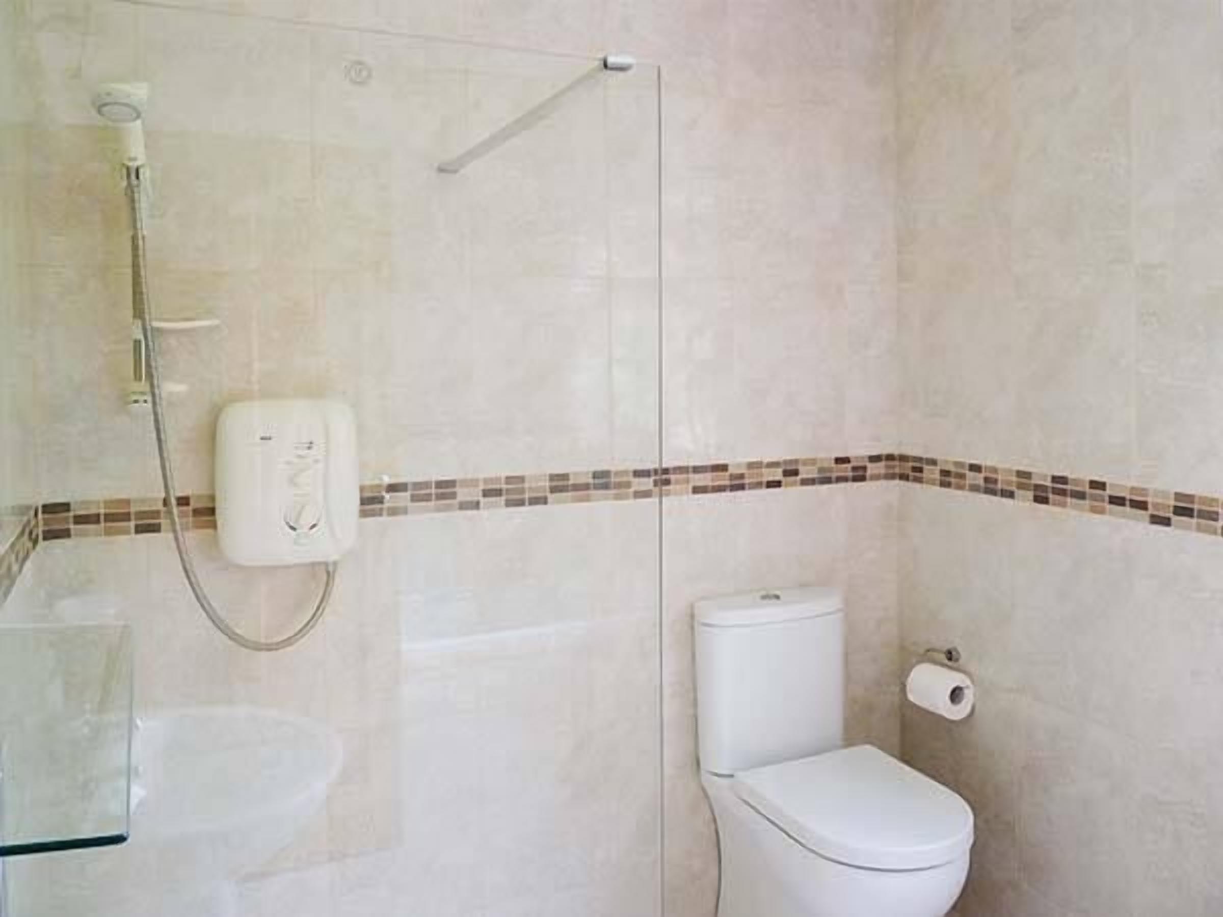 A bathroom with a shower, toilet, and a glass-enclosed sink.
