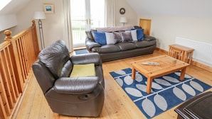 A cozy living room with two leather sofas, a wooden coffee table, and a patterned rug.