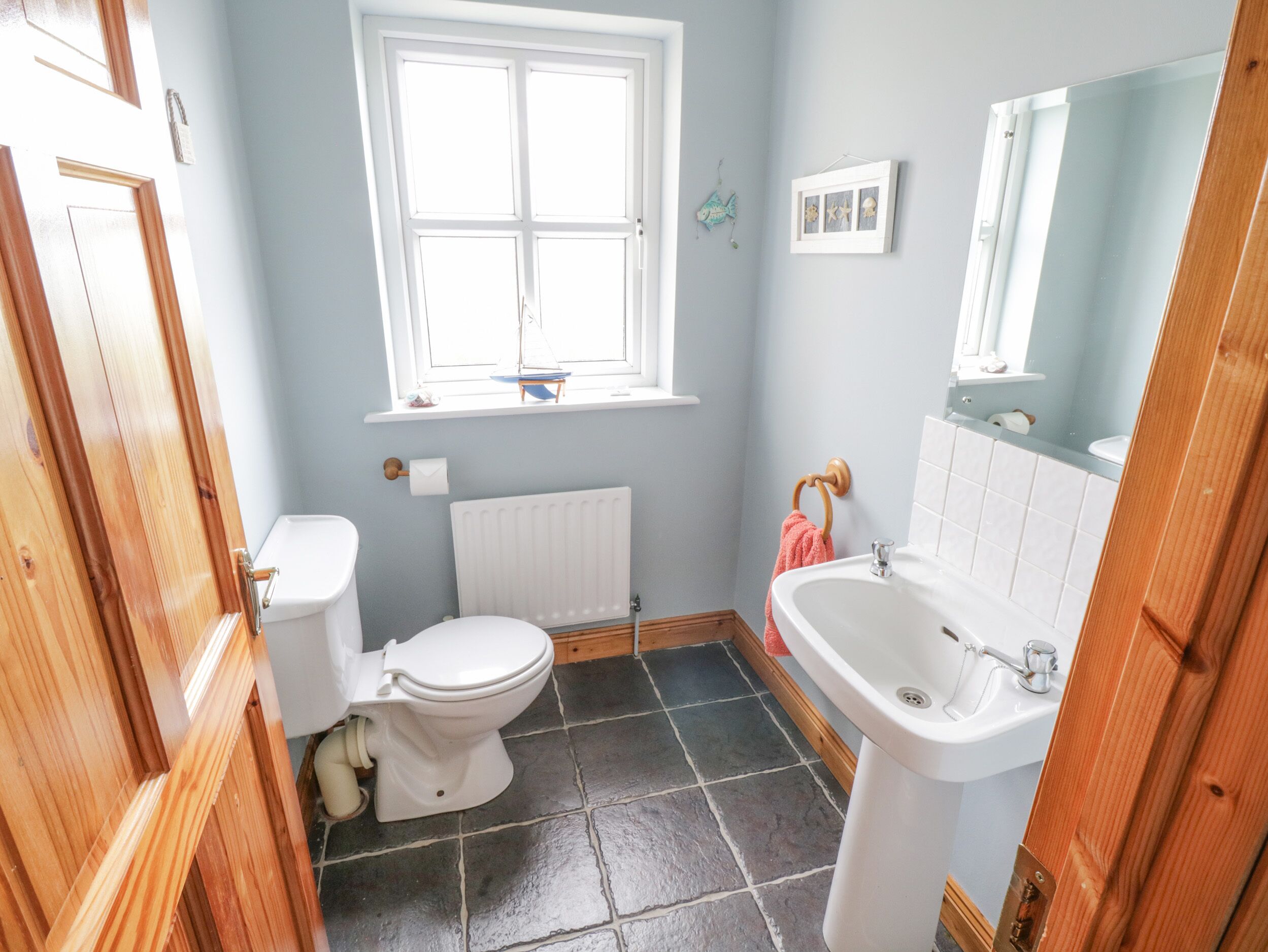 A bathroom with a toilet, sink, and window.