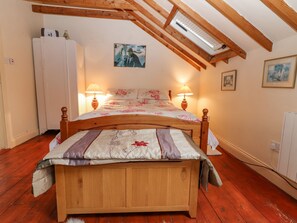 A bedroom with a wooden bed, two bedside lamps, a ceiling fan, and a skylight. - Ryan's Loft (Ardfinnan)