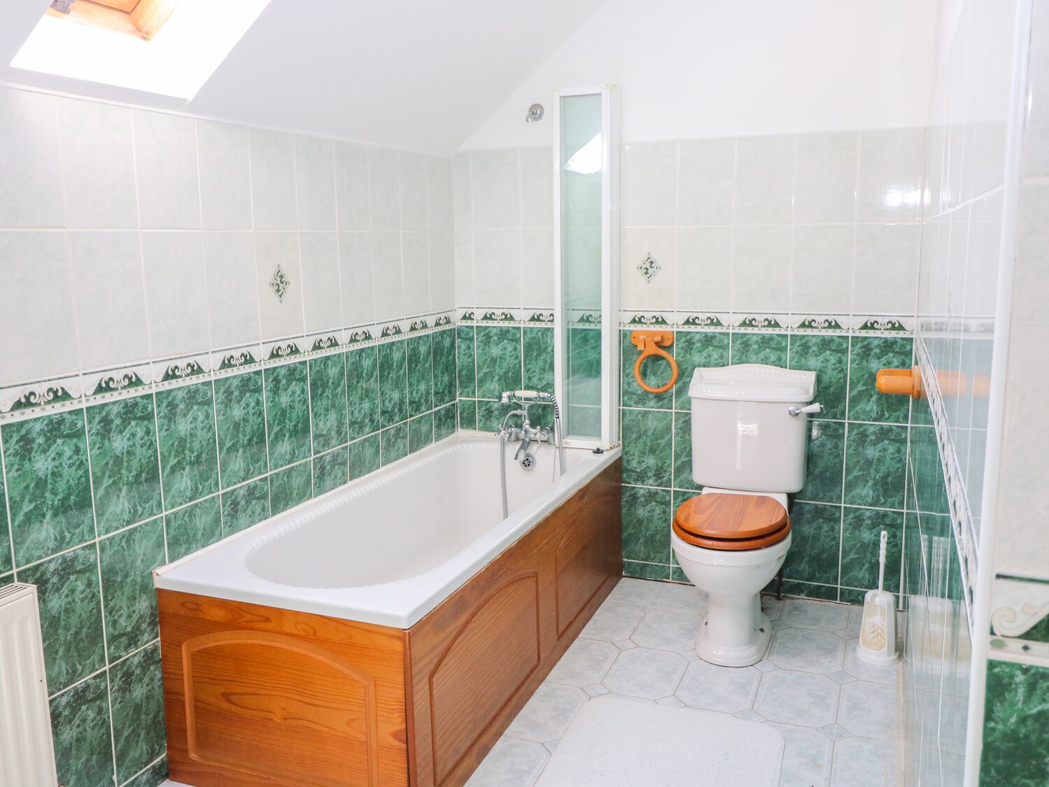 Et badeværelse med et trævandsbad, et hvidt toilet og grøn marmortapeulerings.