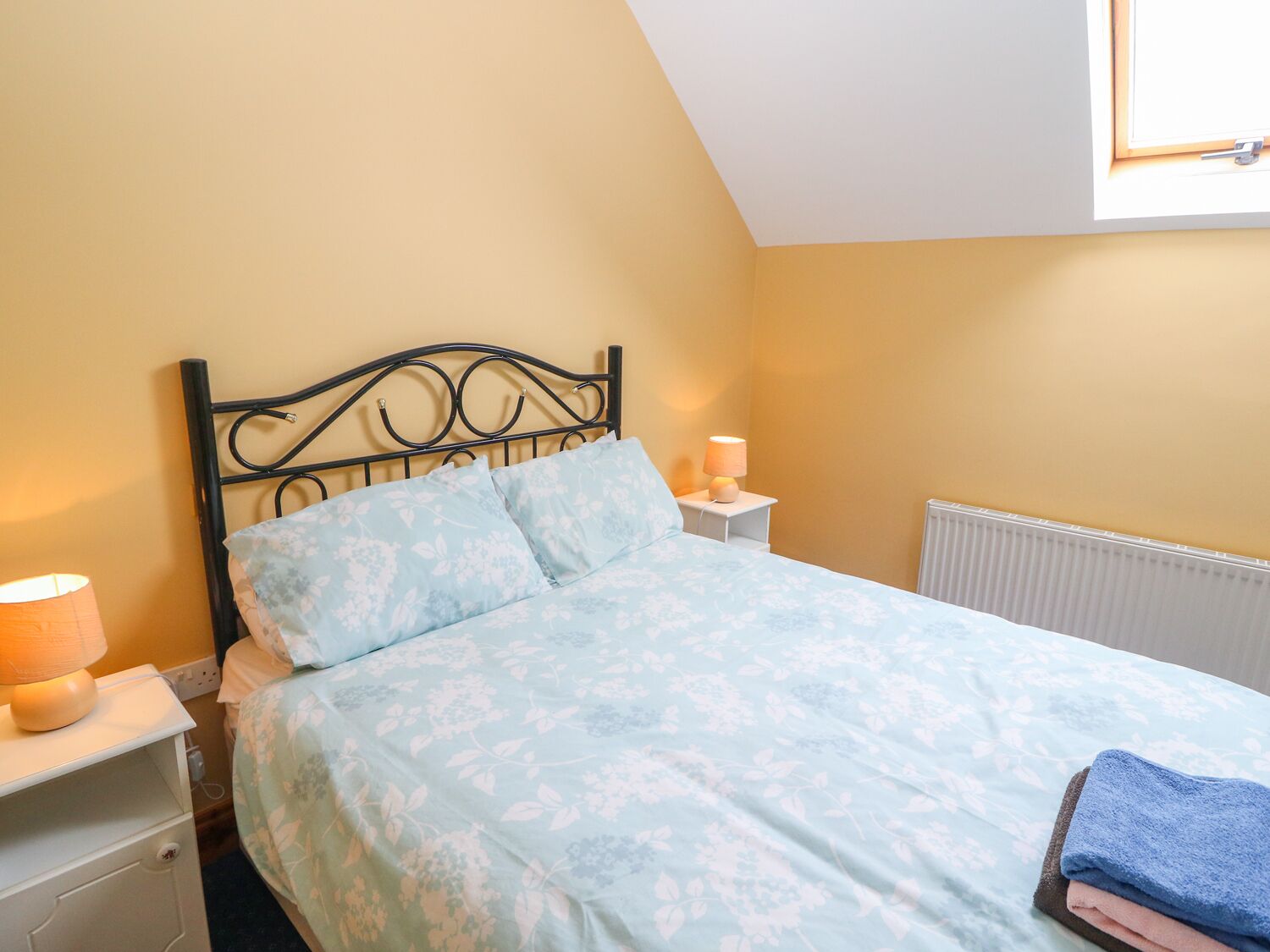 A bedroom with a bed, a nightstand, a lamp, and a radiator.