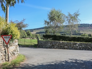 A rural road with a yield sign and a stone wall gate.