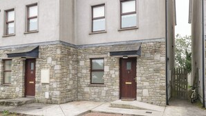 A two-story building with stone and plaster exterior walls, multiple windows, and a wooden door. - Aisling (Foxford)