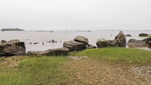 A coastal landscape with large rocks, grassy areas, and a distant island. - Aisling (Foxford)