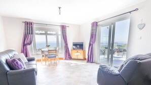 A spacious living area with a sofa, a TV, and a dining table. - Tullyally (Moville)