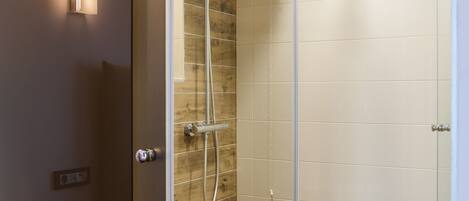 Un baño moderno con cabina de ducha de vidrio, inodoro y aplique de pared.