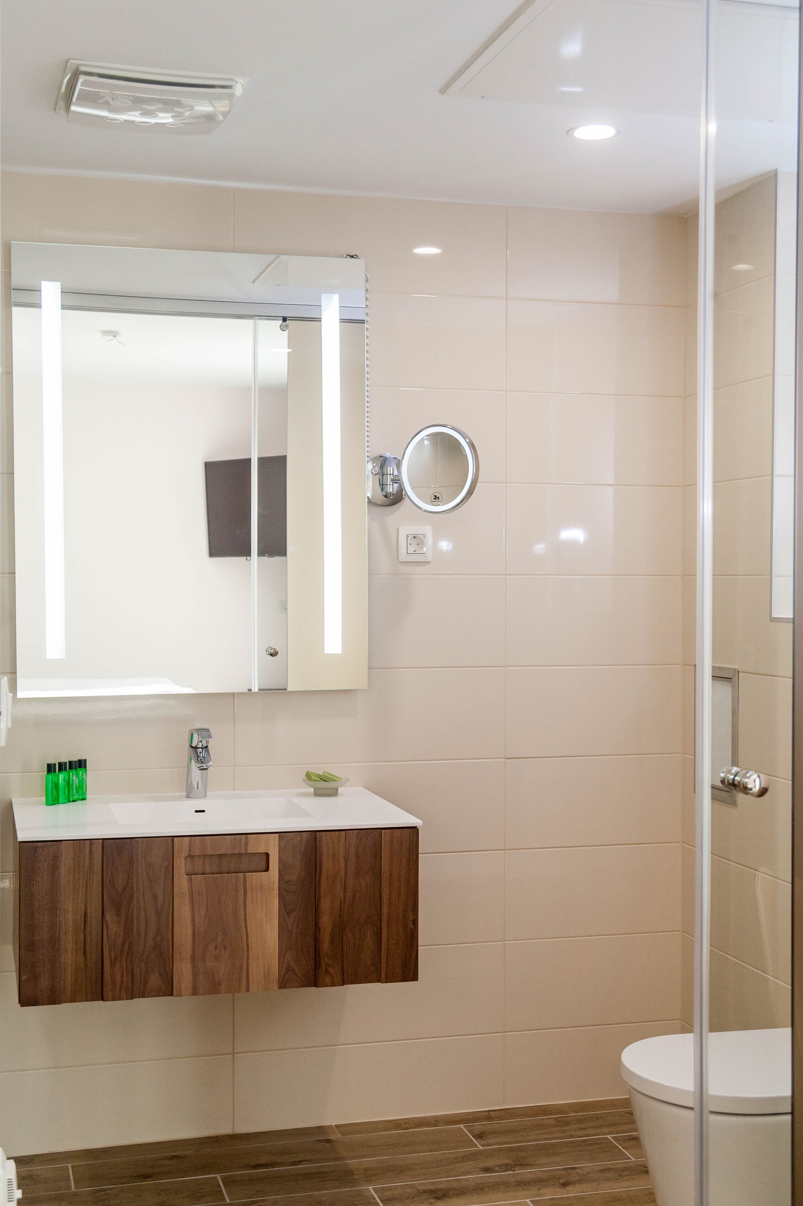 Un baño con lavamanos blanco, tocador de madera, espejo e inodoro.