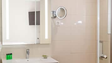 Un baño con lavamanos blanco, tocador de madera, espejo e inodoro.