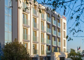 Un moderno edificio hotelero con varios pisos, amplias ventanas y un letrero que indica que es un hotel.
