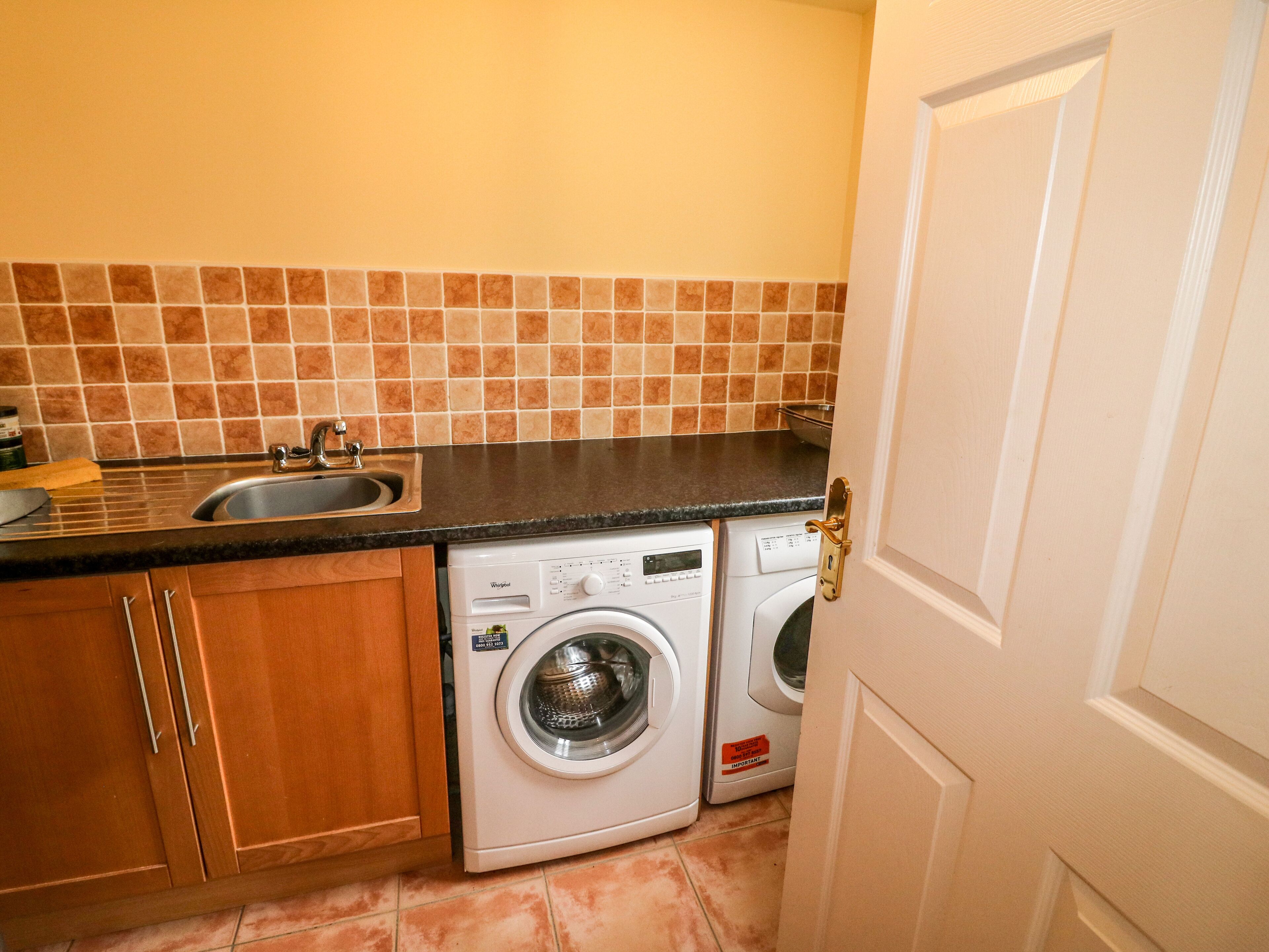 A compact kitchen with a sink, countertop, and two stacked washing machines.