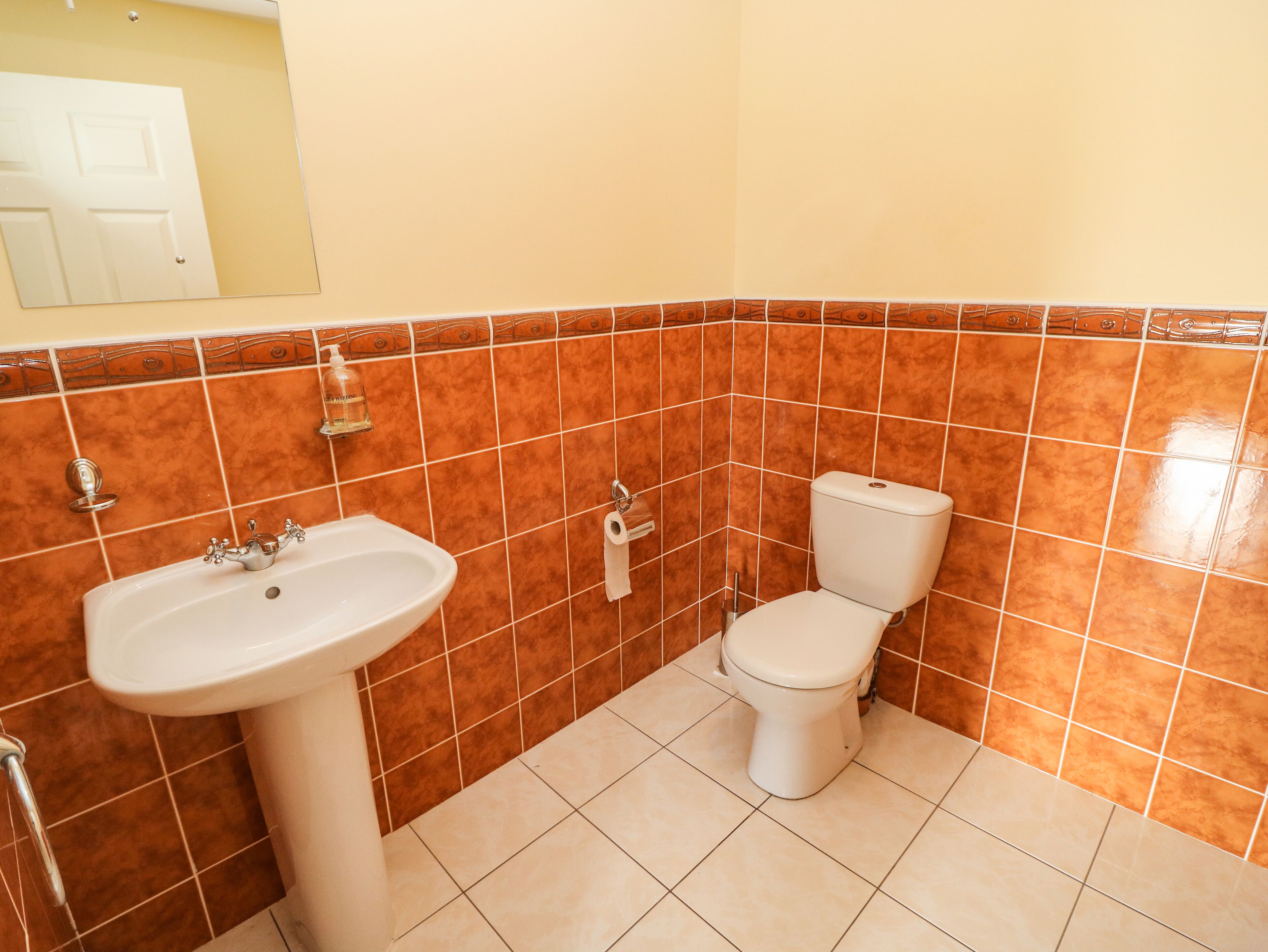 Une salle de bain avec un lavabo, des toilettes et un miroir.
