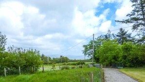A rural landscape with a gravel path, green fields, and trees. - Ferrys (Portsalon)
