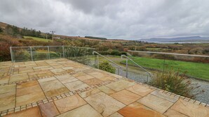 A stone deck with metal railings overlooking a grassy landscape. - Starbay House (Eyeries)