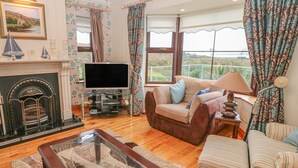 A living room with a fireplace, television, and comfortable seating. - Starbay House (Eyeries)