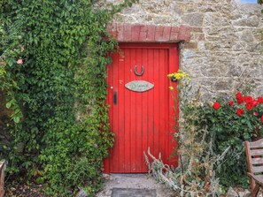 A red door with a metal ring handle and a sign above it.