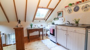 Een gezellige keuken met houten balken, dakraam, een houten tafel en een wit aanrecht.