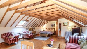 Een gezellig zolderkamer met houten balken, een bed, een bureau en een bank.