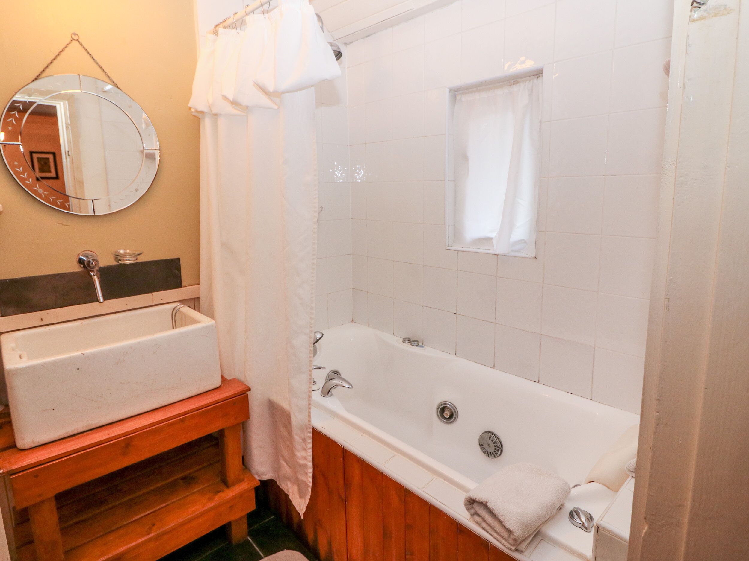 A bathroom with a sink, mirror, and bathtub.